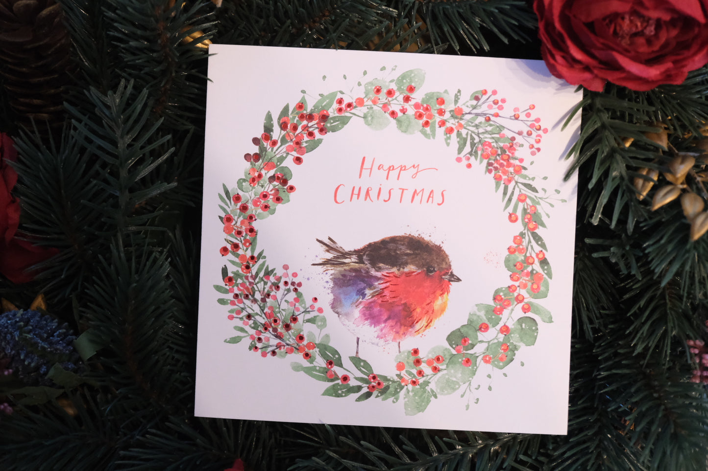 Christmas card containing an illustration of a robin, with a festive background