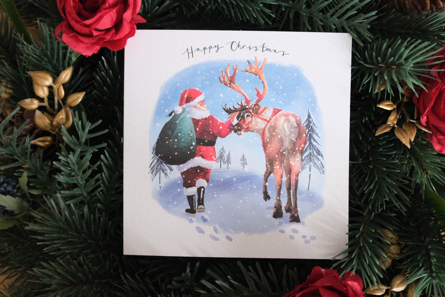 Christmas card with Santa and reindeer surrounded by festive decorations