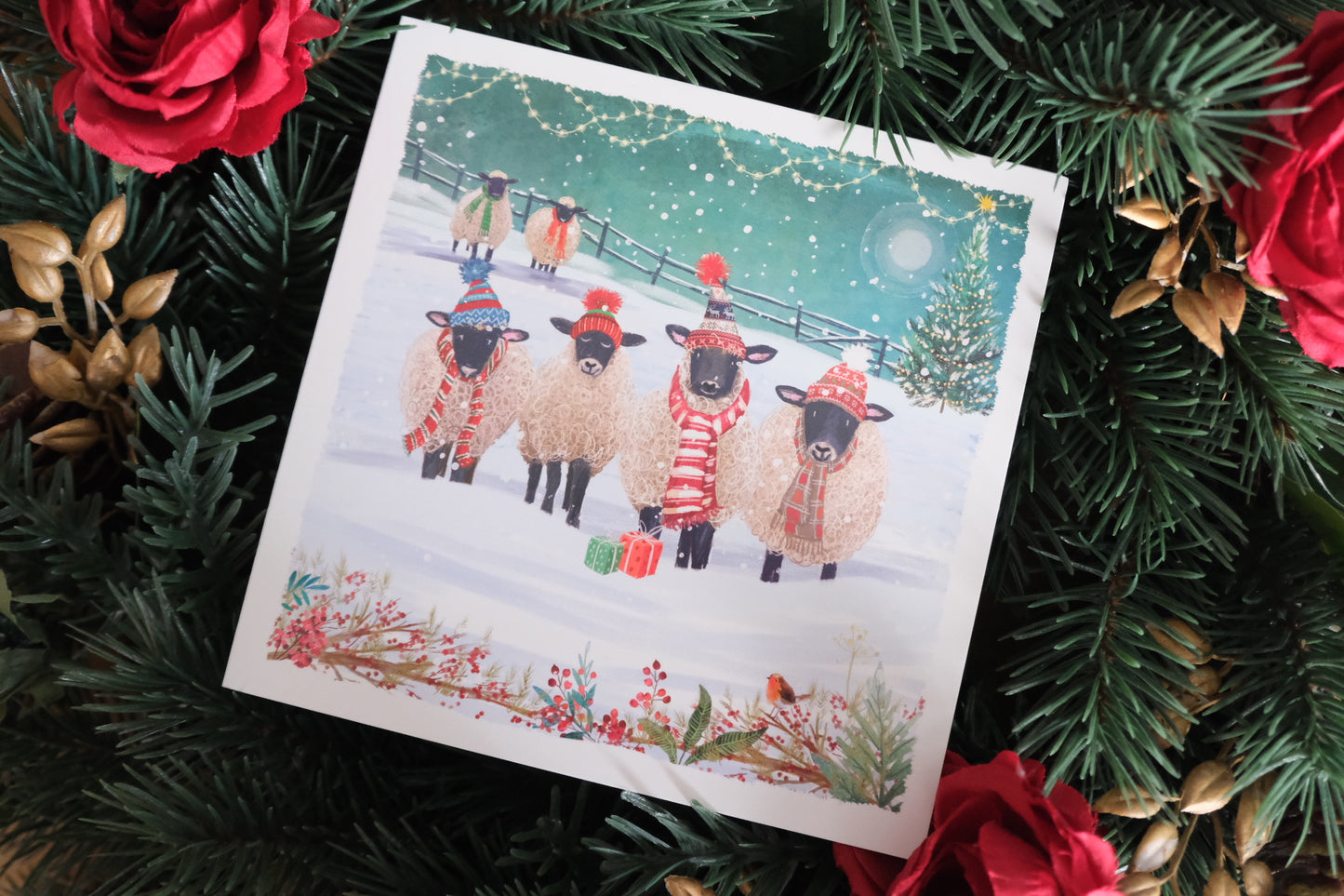 Christmas card with sheep in winter scene surrounded by festive decorations