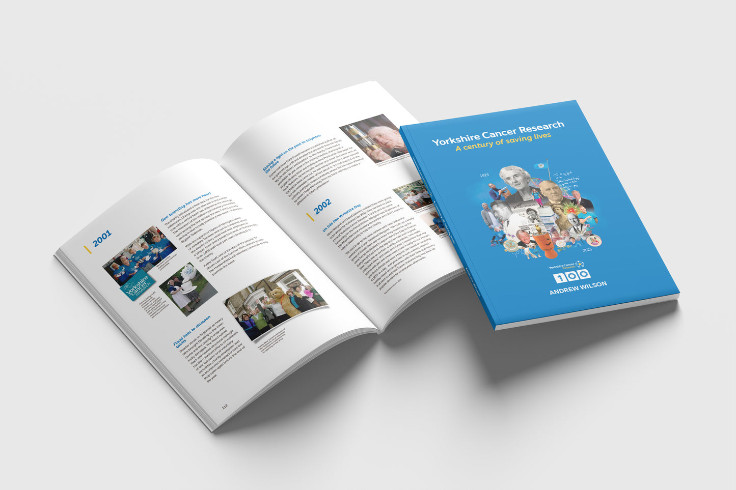 One closed book with a blue cover placed on top of an open copy of the same book